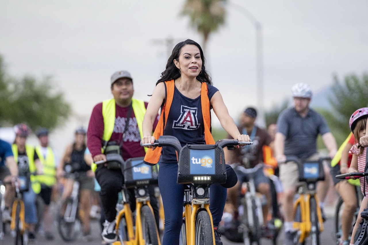 Riders on yellow TUGO bike share bikes during a community ride in Tucson